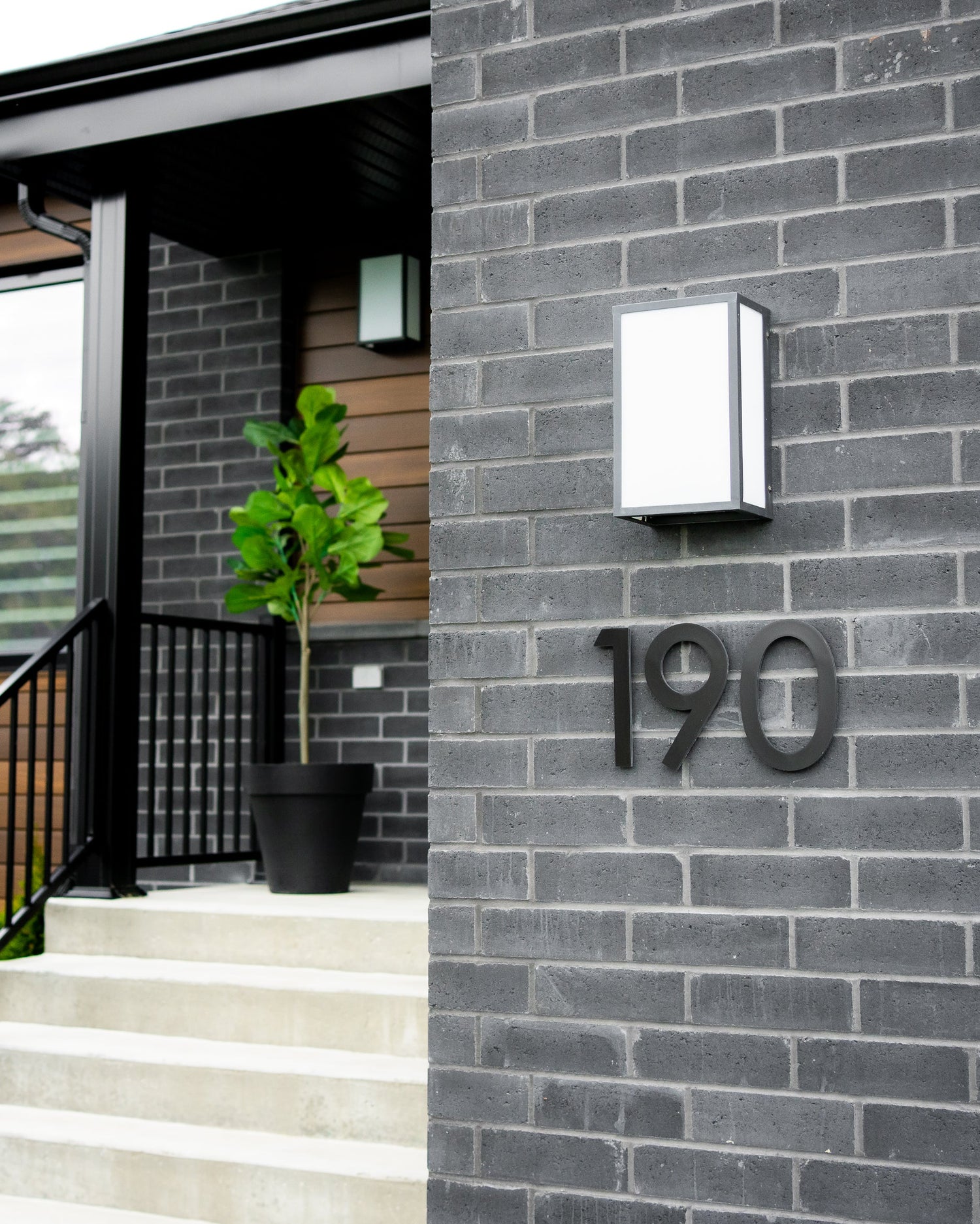 Numéros de porte noirs installés horizontalement sur une façade de brique moderne